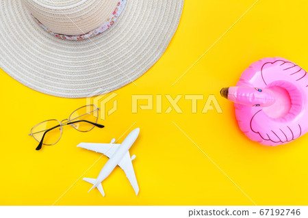 Summer beach composition. Minimal simple flat lay with plane sunglasses hat and Inflatable flamingo isolated on yellow background. Vacation travel adventure trip concept. Top view copy space. 67192746