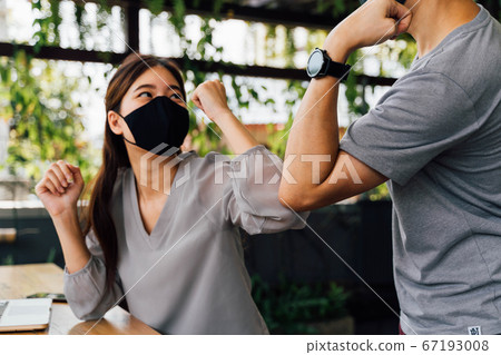 Asian woman and man friends wearing face mask outdoors. Friends greeting and shaking with elbows as new normal. Corona Virus - Covid 19 elbow bumps greeting style to prevent contact and virus spread 67193008
