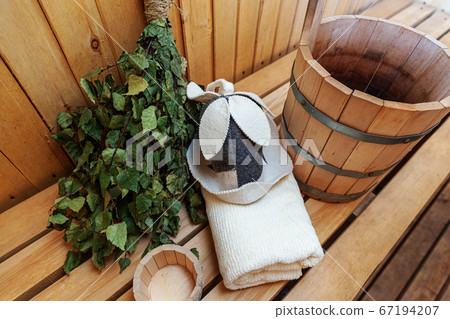 Interior details Finnish sauna steam room with traditional sauna accessories basin birch broom scoop felt hat towel. Traditional old Russian bathhouse SPA Concept. Relax country village bath concept. 67194207