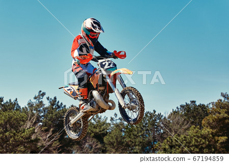 Extreme concept, challenge yourself. Extreme jump on a motorcycle on a background of blue sky with clouds. Copy space, all or nothing. 67194859