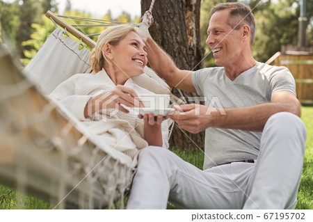 Cheerful mature spouses spending morning together in yard 67195702
