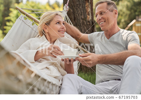 Cheerful couple drinking morning tea together outdoors 67195703