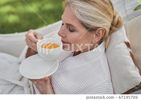 Serene female having cup of hot drink outdoors 67195709