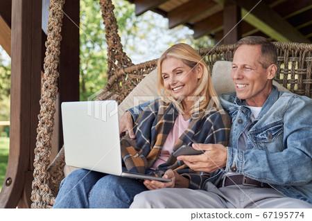 Merry mature couple with modern gadgets outdoors 67195774