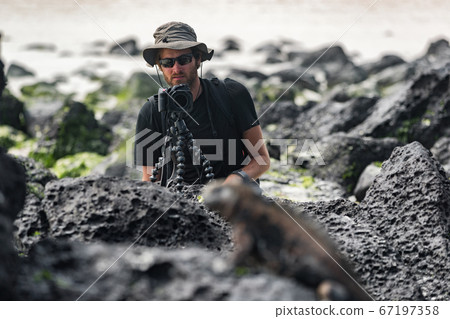 Wildlife photographer and tourist on Galapagos taking photo of Marine Iguana 67197358