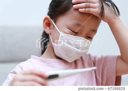 An infant who is in poor physical condition wearing a mask to measure body temperature 67198829
