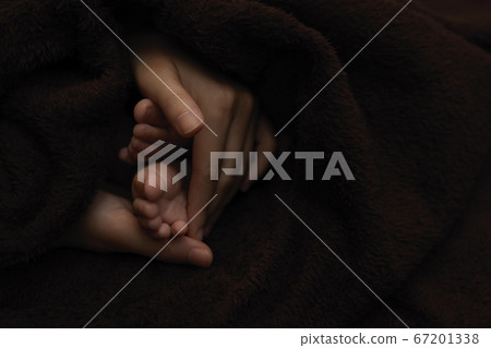 Mother hands  holding newborn baby feet, dark 67201338