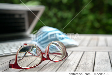 Work at home. Medical face mask on top of computer 67203400