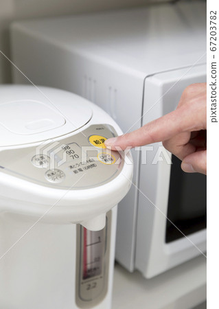 Woman hand pressing hot water button on electric kettle Woman hand pressing hot water button on electric kettle 67203782