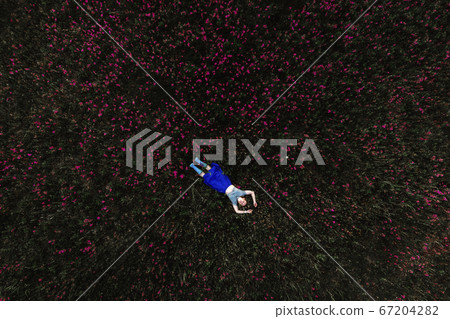 Woman lying on green grass in park 67204282