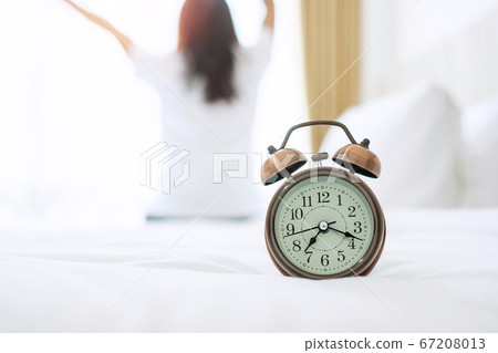 Closeup alarm clock with background of happy woman Closeup alarm clock with background of happy woman 67208013
