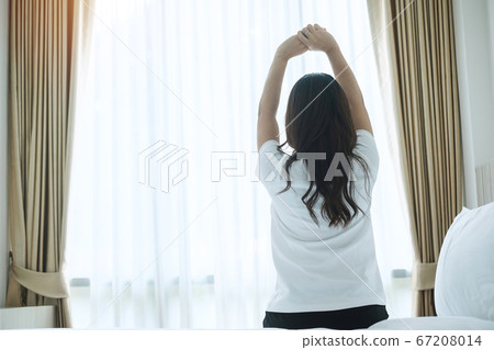 happy woman stretching in bed after waking up, happy woman stretching in bed after waking up, 67208014