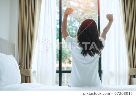 happy woman stretching in bed after waking up, 67208015
