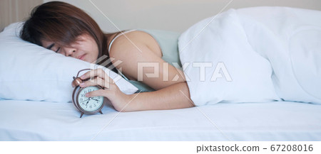 alarm clock and asian woman hand stop time in bed 67208016