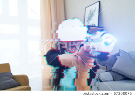 Woman with virtual reality headset is playing game. Image with glitch effect. Woman with virtual reality headset is playing game. Image with glitch effect. 67208076