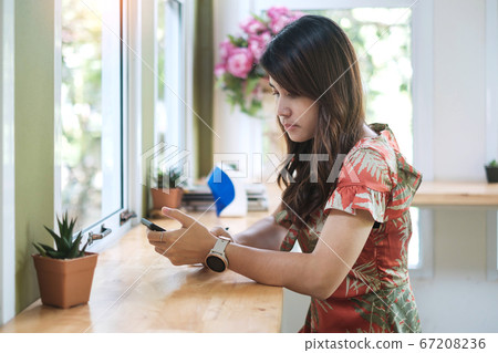 Happy woman sitting and using smart mobile phone 67208236