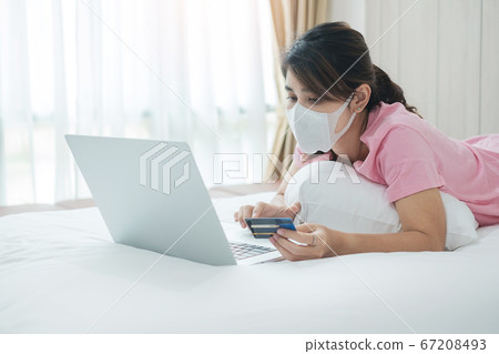 Sickness woman with face mask holding credit card Sickness woman with face mask holding credit card 67208493