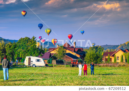 Colorful hot air balloons flying over the village Transylvania, Romania 67209512