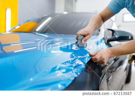 Car wrapping, mechanic with squeegee installs film Car wrapping, mechanic with squeegee installs film 67213087