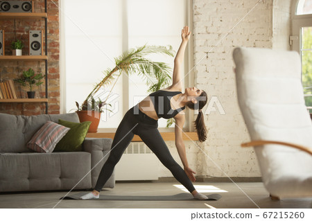 Sporty young muslim woman taking yoga lessons online and practice at home 67215260