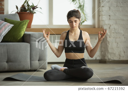 Sporty young muslim woman taking yoga lessons online and practice at home Sporty young muslim woman taking yoga lessons online and practice at home 67215392