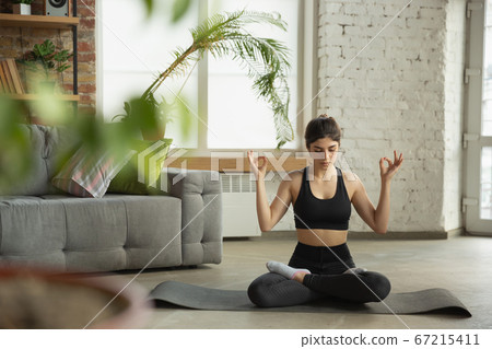 Sporty young muslim woman taking yoga lessons online and practice at home 67215411