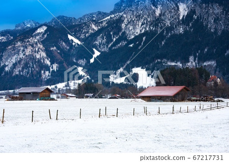 Wooden shed in snowy field against Alps in winter Wooden shed in snowy field against Alps in winter 67217731