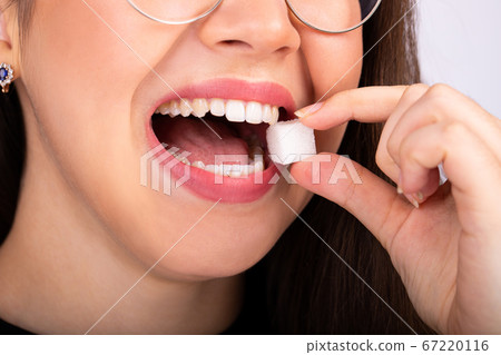 young woman in glasses bites a piece of white sugar 67220116