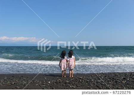 Twin girls staring at the sea Twin girls staring at the sea 67220276