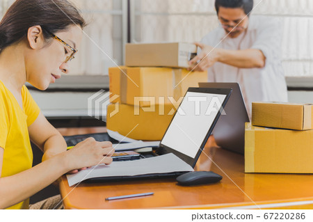 Business couple hand writing address on parcel box work from home. 67220286