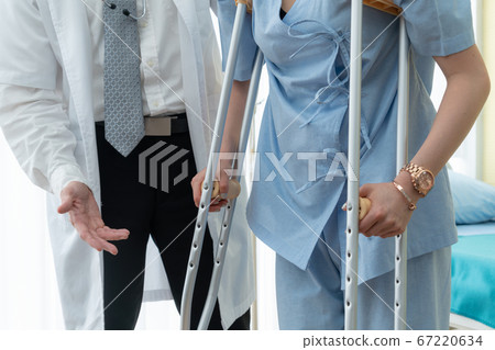 Doctor takes care of patient in crutch at hospital 67220634
