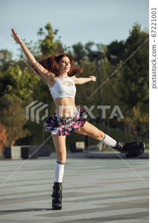 Beautiful woman in sportswear jumping in a kangoo jumps shoes at the street on summer's sunny day 67221001