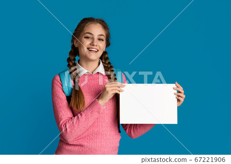 Smiling girl school girl holds white sheet with empty space 67221906