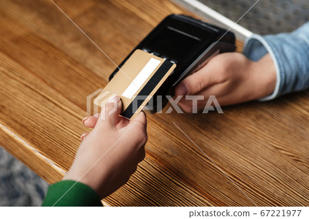 Modern technology for paying bills. Client pays by credit card at contactless terminal Modern technology for paying bills. Client pays by credit card at contactless terminal 67221977