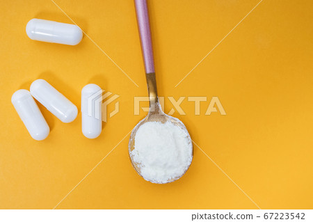 Collagen powder and pills on yellow background 67223542