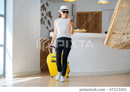 Adult woman with luggage with suitcase going to the hotel lobby Adult woman with luggage with suitcase going to the hotel lobby 67223891
