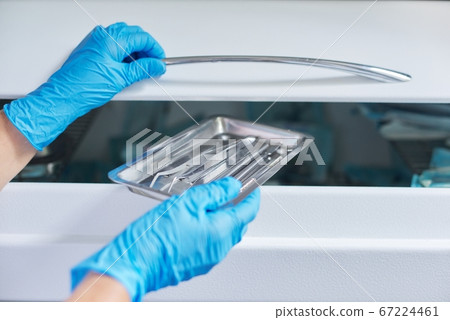 Female nurse doing sterilization of dental medical instruments in autoclave Female nurse doing sterilization of dental medical instruments in autoclave 67224461