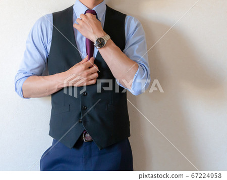 一個穿著西裝站在他的襯衫的男人捲起 67224958