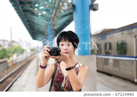 mature Asian woman using digital camera mature Asian woman using digital camera 67224990
