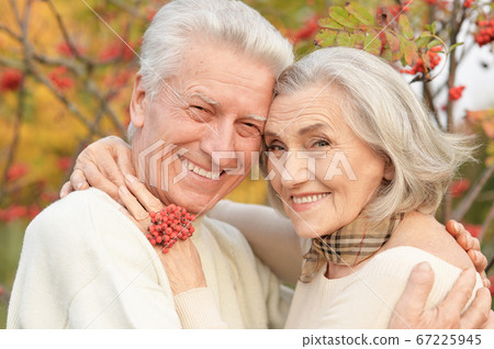 Beautiful senior couple hugging in the park with rowan berries 67225945