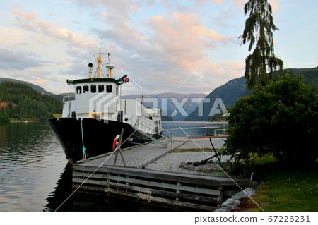 挪威哈當厄爾峽灣，在烏爾維克飯店東南部的碼頭從午夜的陽光中俯瞰一艘小型觀光船 67226231