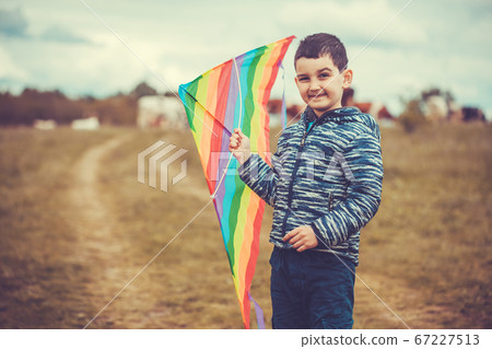 Little boy in blue shirt running with kite on the meadow 67227513