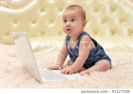 Cute little baby girl on bed with laptop 67227596