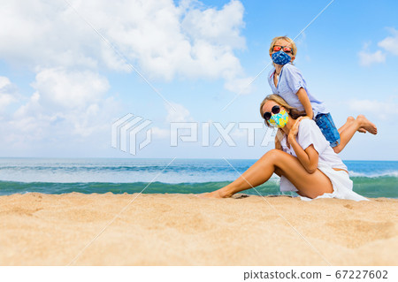 Mother, child in face masks have fun on sea beach Mother, child in face masks have fun on sea beach 67227602