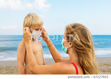 Mother put face mask on child on sea beach Mother put face mask on child on sea beach 67227603