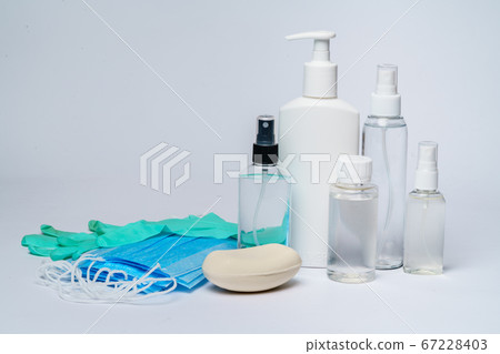 bottle of lotion, sanitizer or liquid soap and protective mask over light grey background 67228403