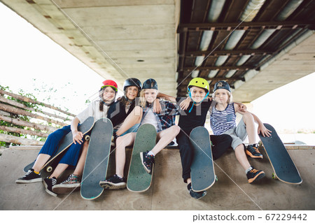 Extreme sport in city. Skateboarding Club for children. Group friends posing on ramp at skatepark. Early adolescence in skate training. Friends skateboarders on street platform for skating on board Extreme sport in city. Skateboarding Club for children. Group friends posing on ramp at skatepark. Early adolescence in skate training. Friends skateboarders on street platform for skating on board 67229442