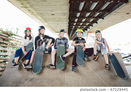 Extreme sport in city. Skateboarding Club for children. Group friends posing on ramp at skatepark. Early adolescence in skate training. Friends skateboarders on street platform for skating on board Extreme sport in city. Skateboarding Club for children. Group friends posing on ramp at skatepark. Early adolescence in skate training. Friends skateboarders on street platform for skating on board 67229445