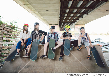 Happy friends in city park for extreme sports. Little ones having fun on skating ramp outdoor . Youth and friendship. Caucasian riders having fun together on sports urban area for skateboarding Happy friends in city park for extreme sports. Little ones having fun on skating ramp outdoor . Youth and friendship. Caucasian riders having fun together on sports urban area for skateboarding 67229447