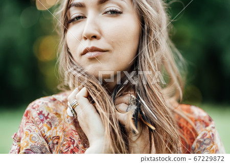 Portrait of Beautiful young woman wearing bohostyle clothes posing in the rays of the evening sun, sunset. Boho style fashion, female wearing silver jewelry having fun in park outdoors. Portrait of Beautiful young woman wearing bohostyle clothes posing in the rays of the evening sun, sunset. Boho style fashion, female wearing silver jewelry having fun in park outdoors. 67229872